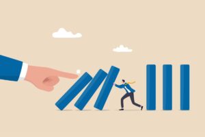 ilustração de um homem segurando placas, como dominos, e uma mão empurando as peças. Representando riscos